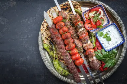 Grillplatte mit Spießen, Fladenbrot, Salat und Dips